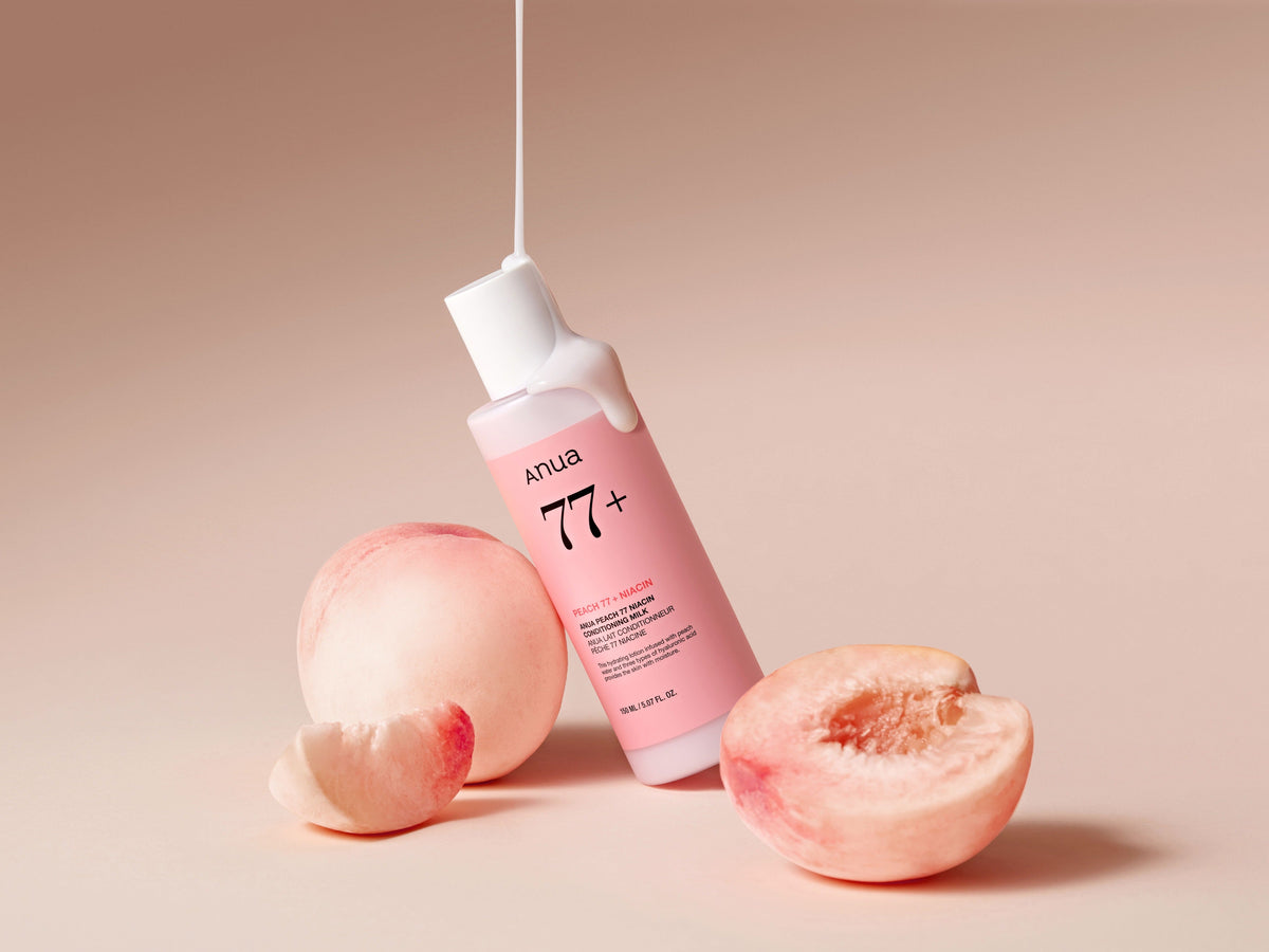 Lait hydratant coulant sur un flacon rose entouré de pêches