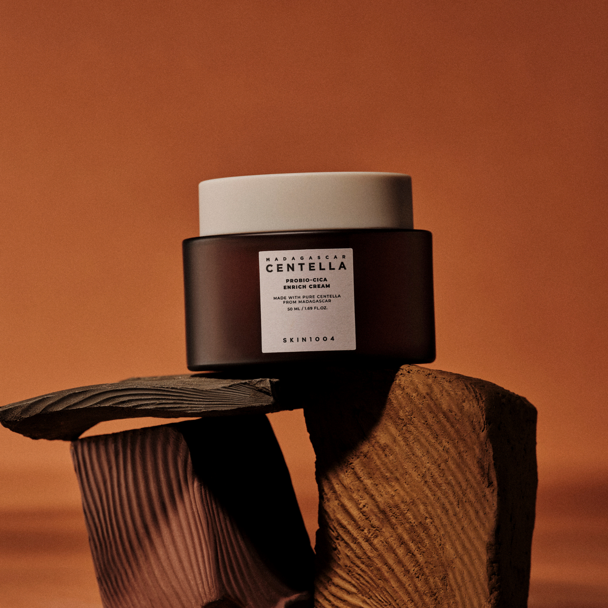 Pot brun de crème à couvercle beige posé sur des morceaux de bois