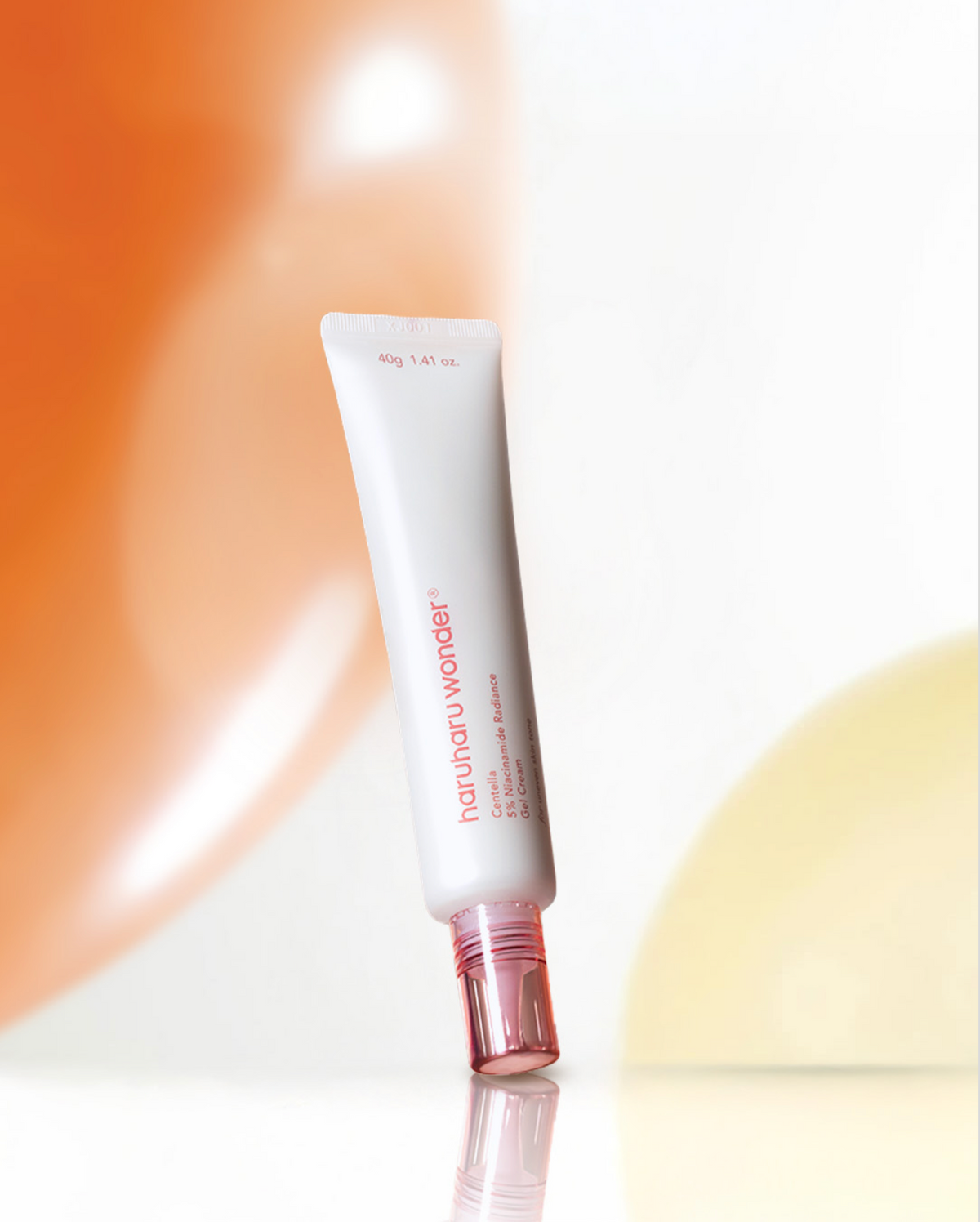 Tube fin de gel-crème à bouchon rose sur un fond orange et blanc
