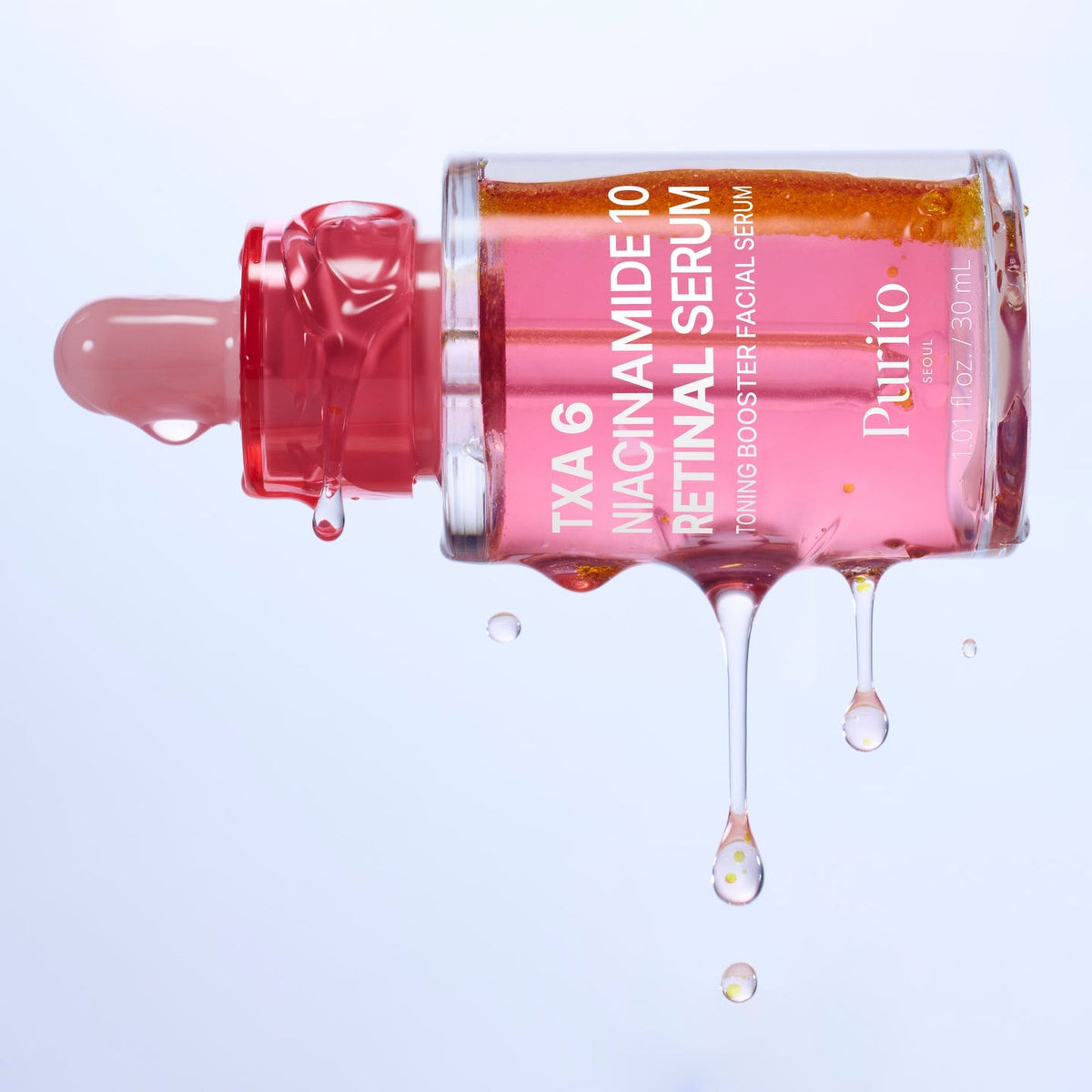 Flacon de sérum rose avec des particules jaunes et des gouttes qui s&