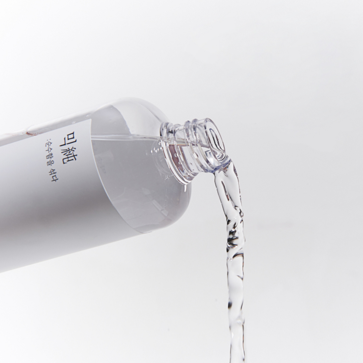 Lotion transparente versée depuis le flacon incliné