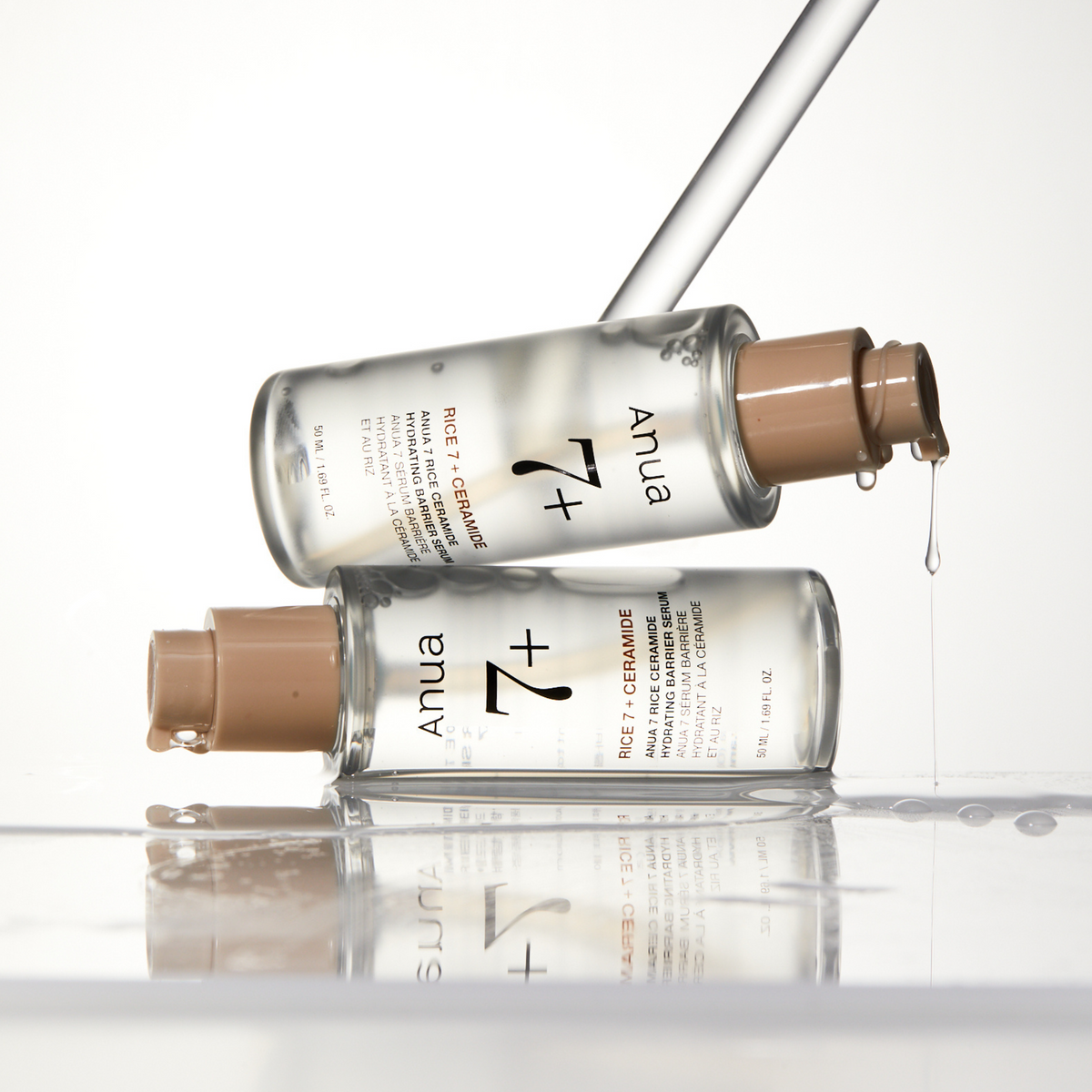 Deux flacons-pompes de sérum transparent inclinés, avec des gouttes aux embouts