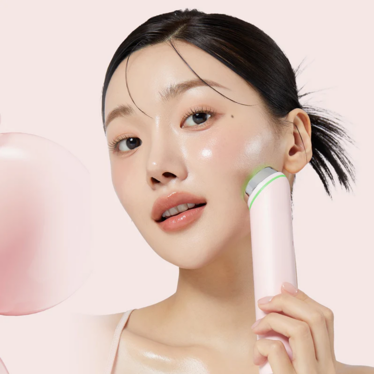 Appareil rose à tête lumineuse verte posé contre la joue