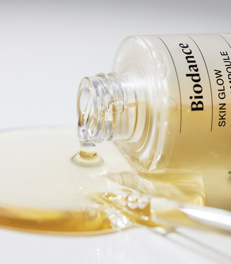 Ampoule dorée répandue près du flacon ouvert et de sa pipette