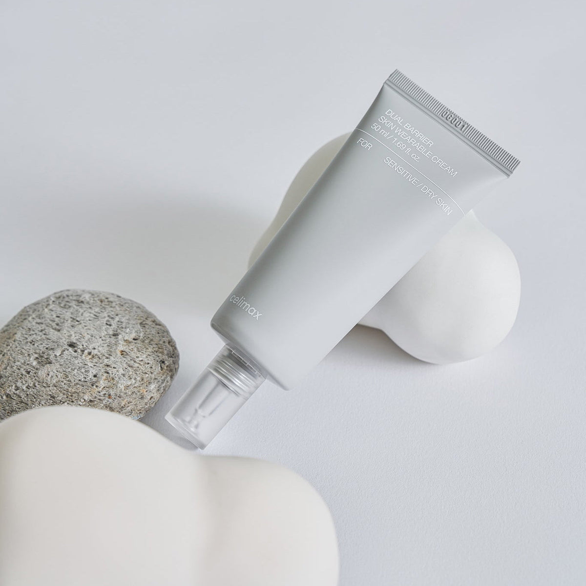 Tube-pompe gris de crème disposé parmi des pierres