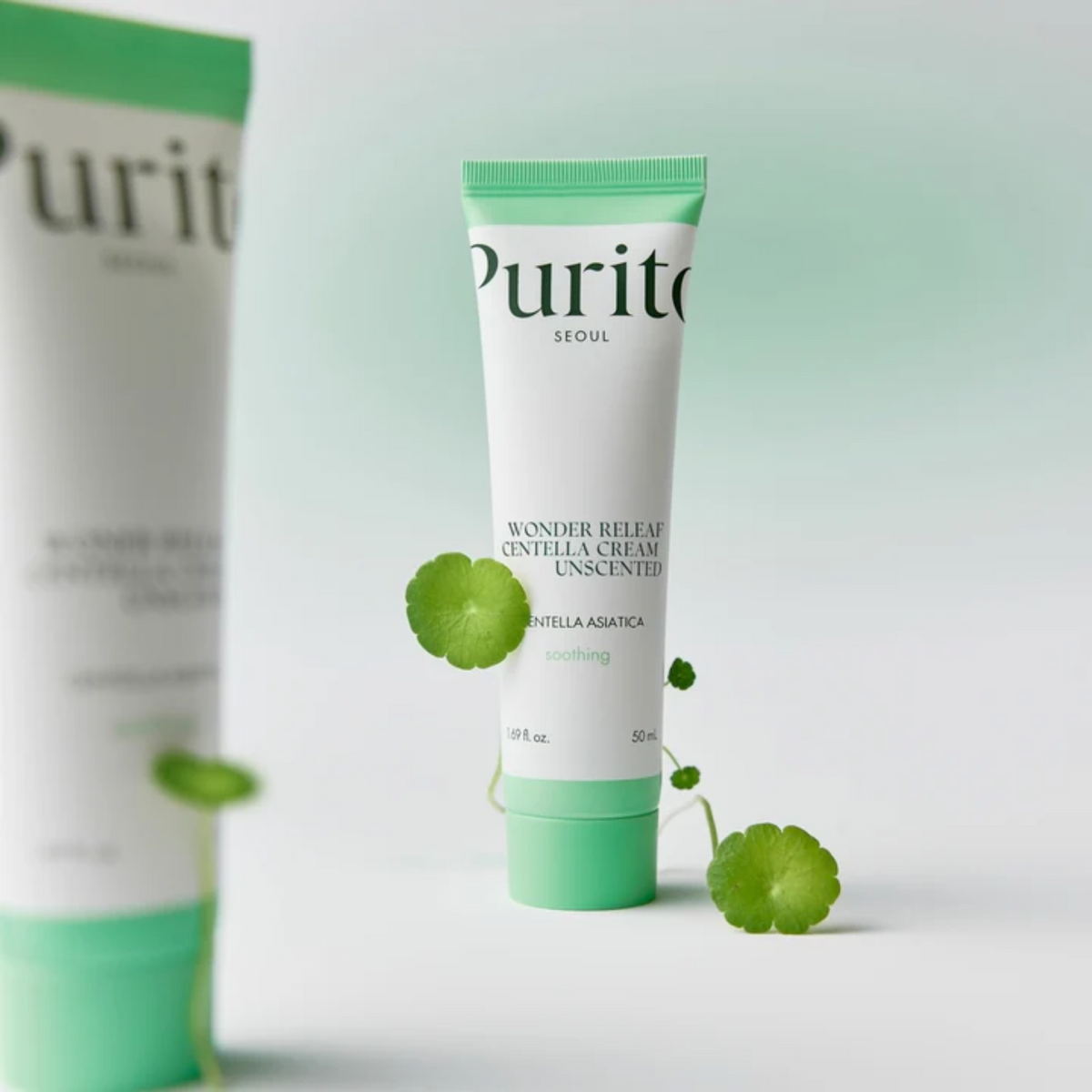 Tube de crème sans parfum à bouchon vert près de feuilles de centella