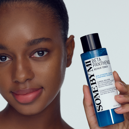 Flacon bleu de lotion tenu près du visage