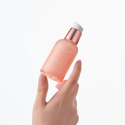 Flacon-pompe rose de sérum tenu du bout des doigts