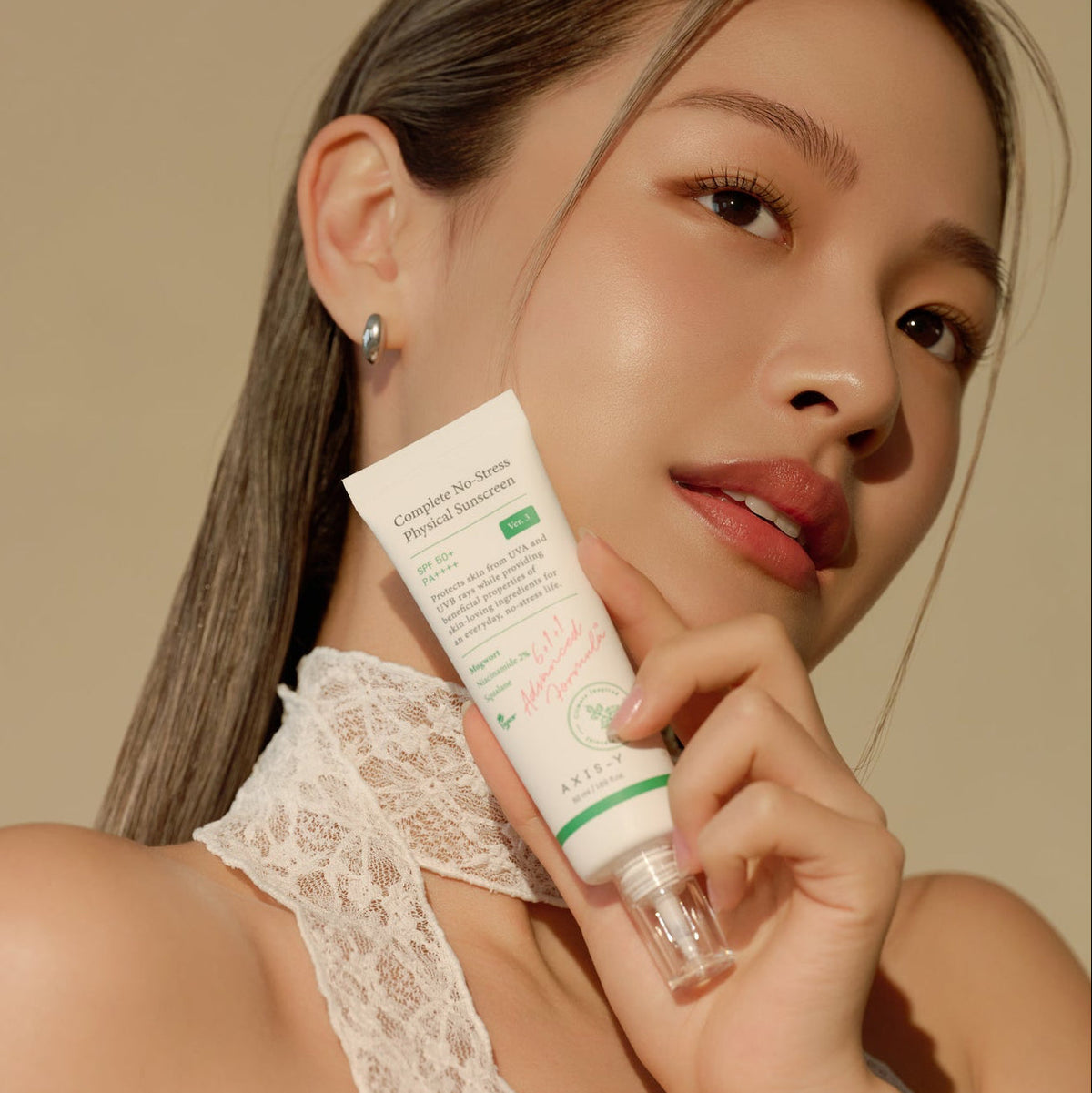 Tube de crème solaire tenu près du visage