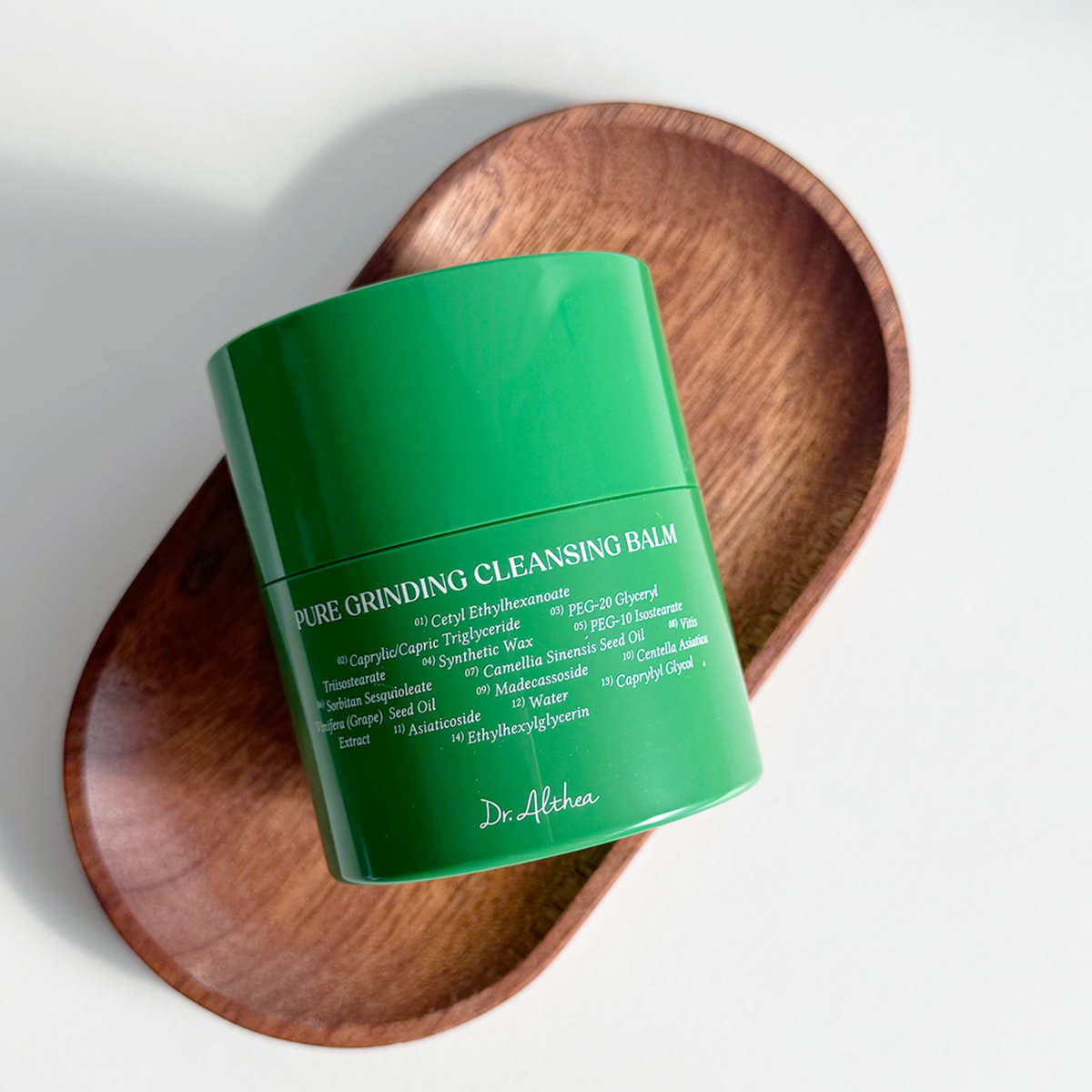 Pot vert fermé de baume nettoyant posé sur un plateau en bois