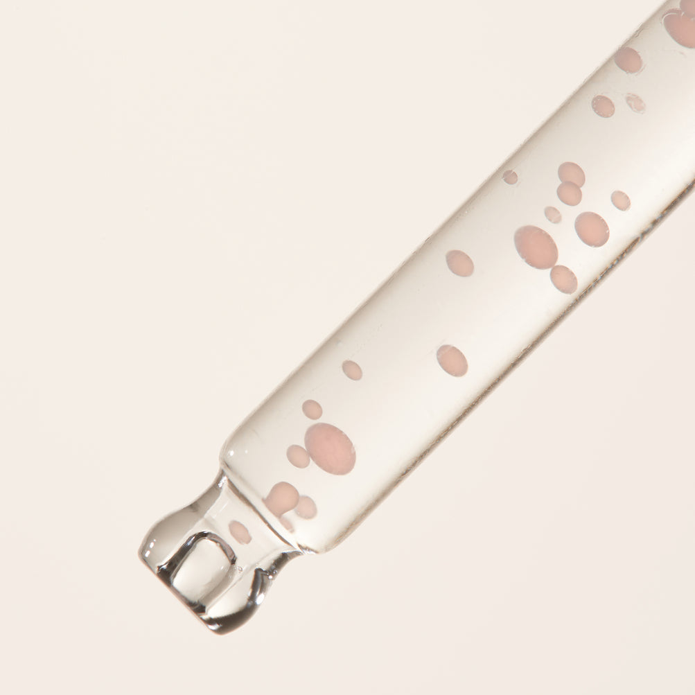 Pipette transparente remplie de petites capsules roses
