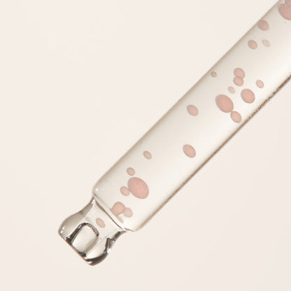 Pipette transparente remplie de petites capsules roses