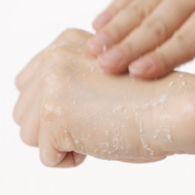 Gel exfoliant massé sur le dos de la main avec des résidus blancs