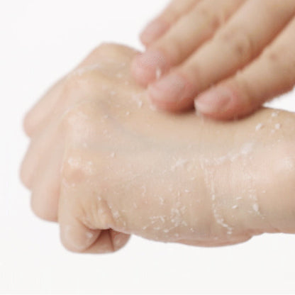 Gel exfoliant massé sur le dos de la main avec des résidus blancs