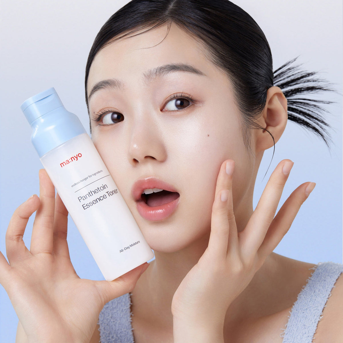 Flacon de lotion tenu près du visage, une main sur la joue