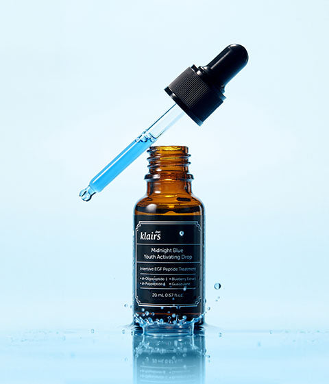 Pipette de sérum bleu au-dessus du flacon posé sur l&