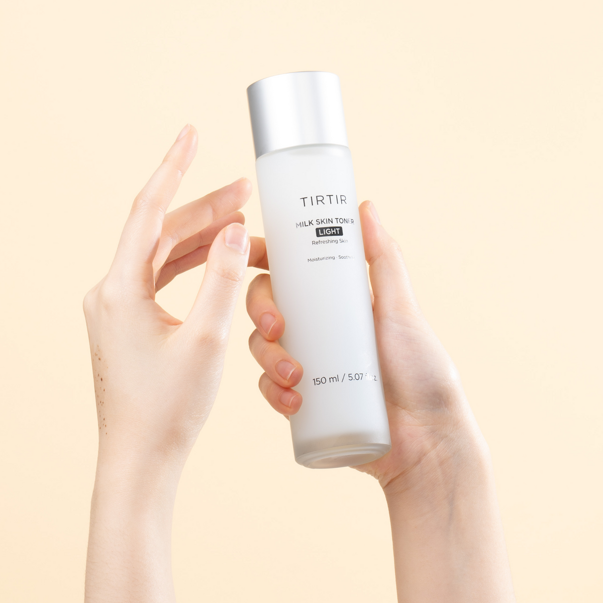 Flacon de lotion Light présenté entre deux mains