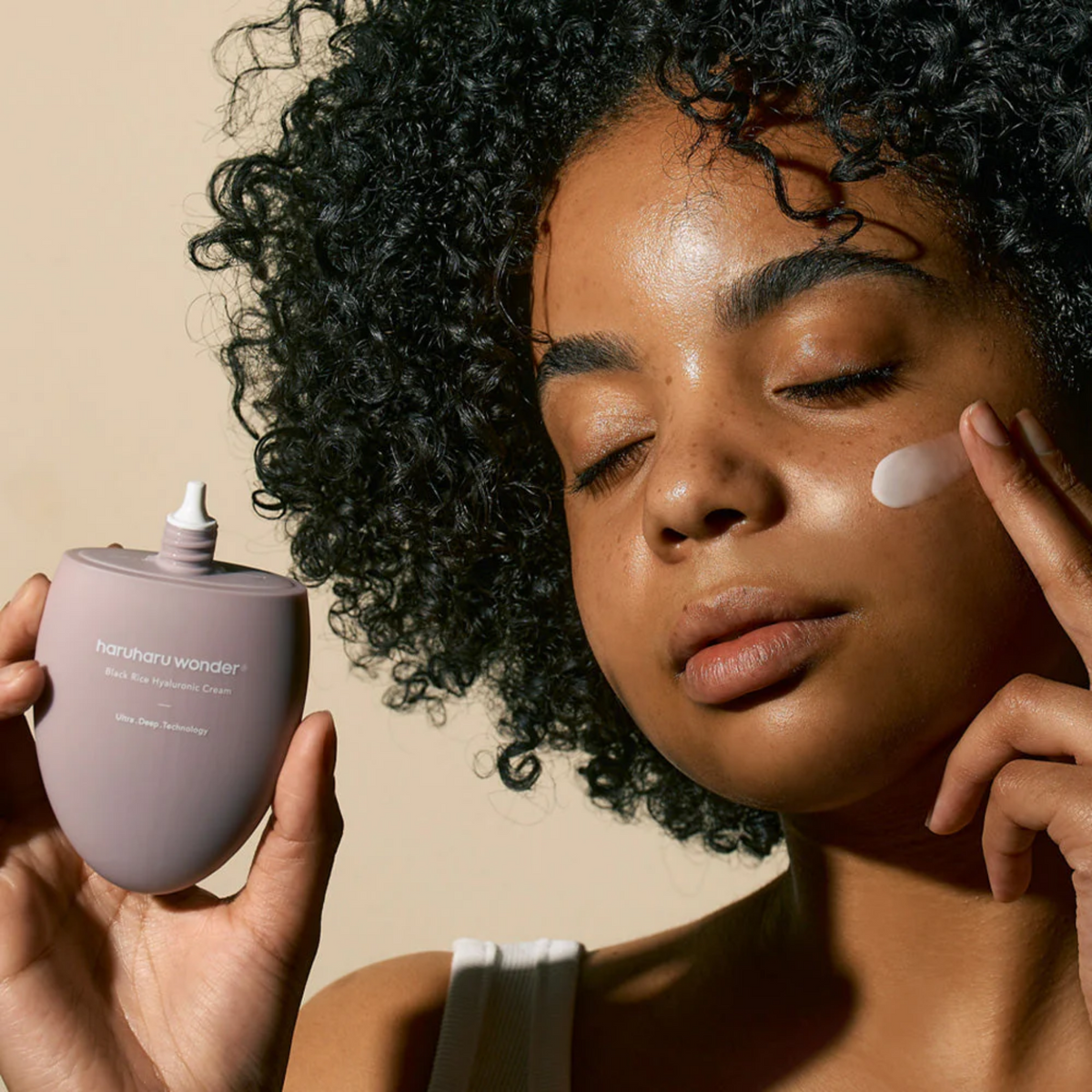 Crème déposée sur la joue près du flacon ouvert