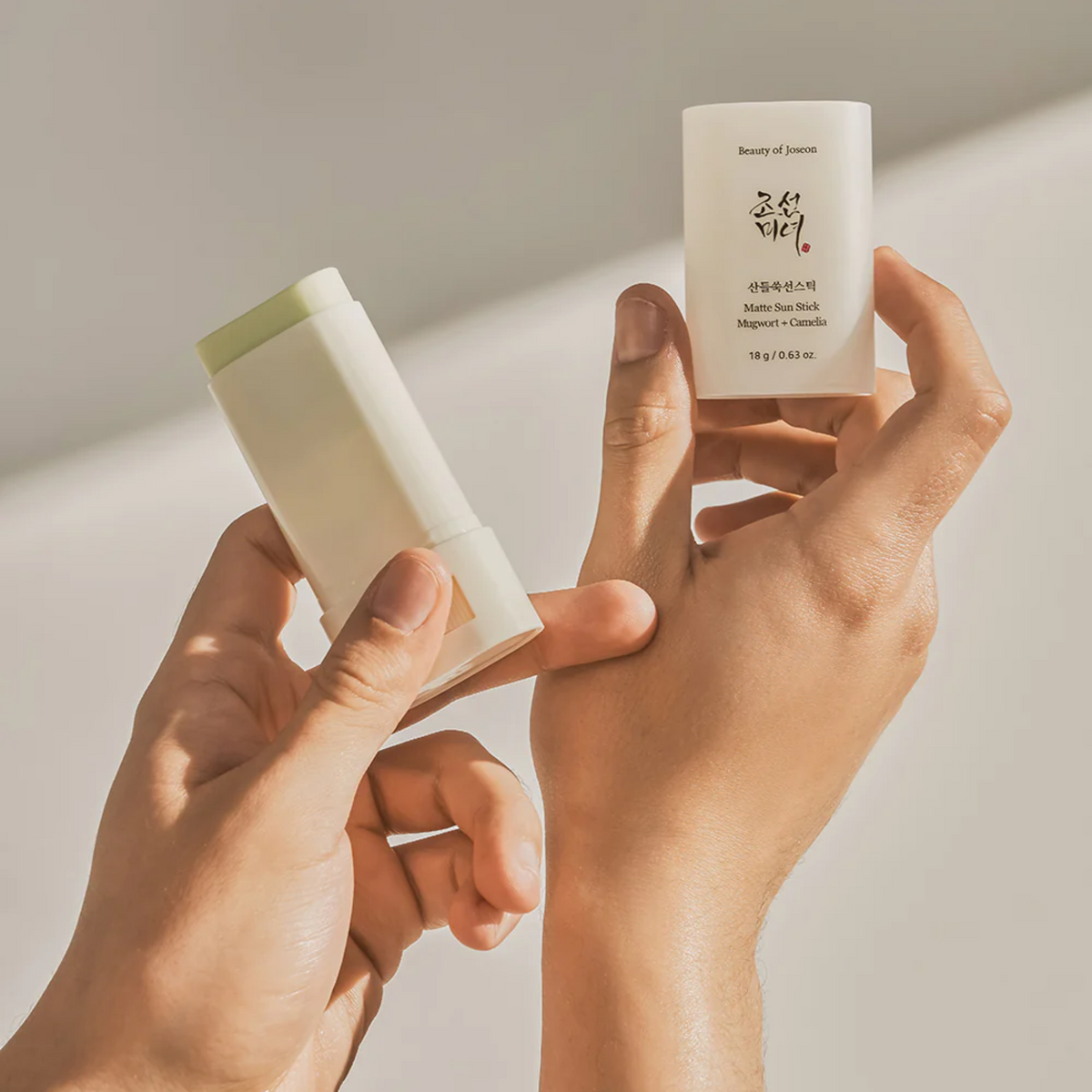 Stick solaire ouvert et capuchon tenus dans les mains