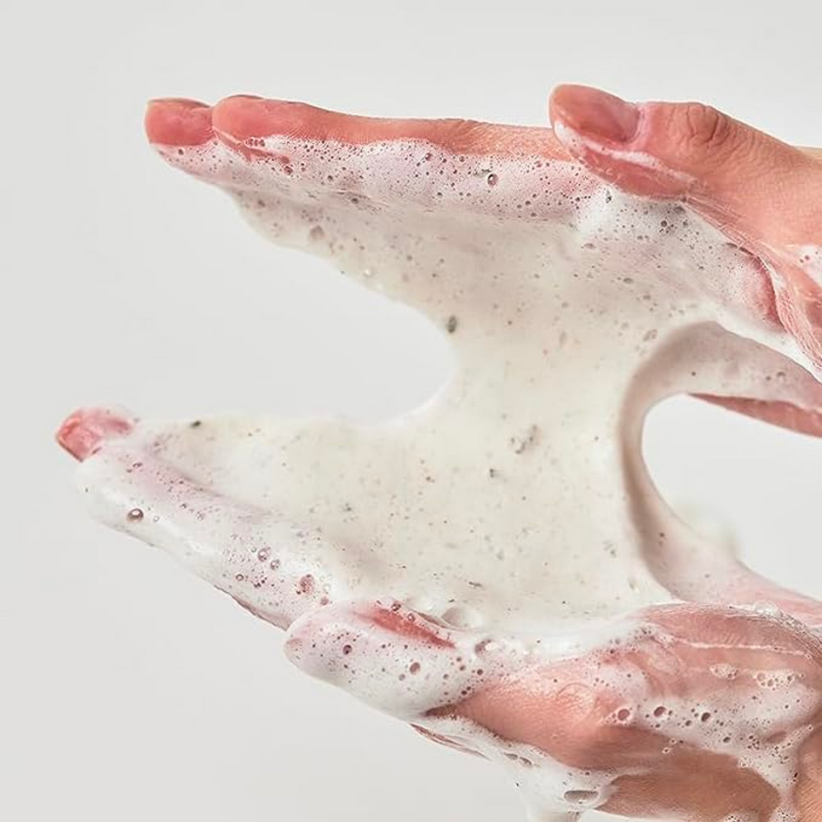 Mousse nettoyante à fines particules étirée entre les mains