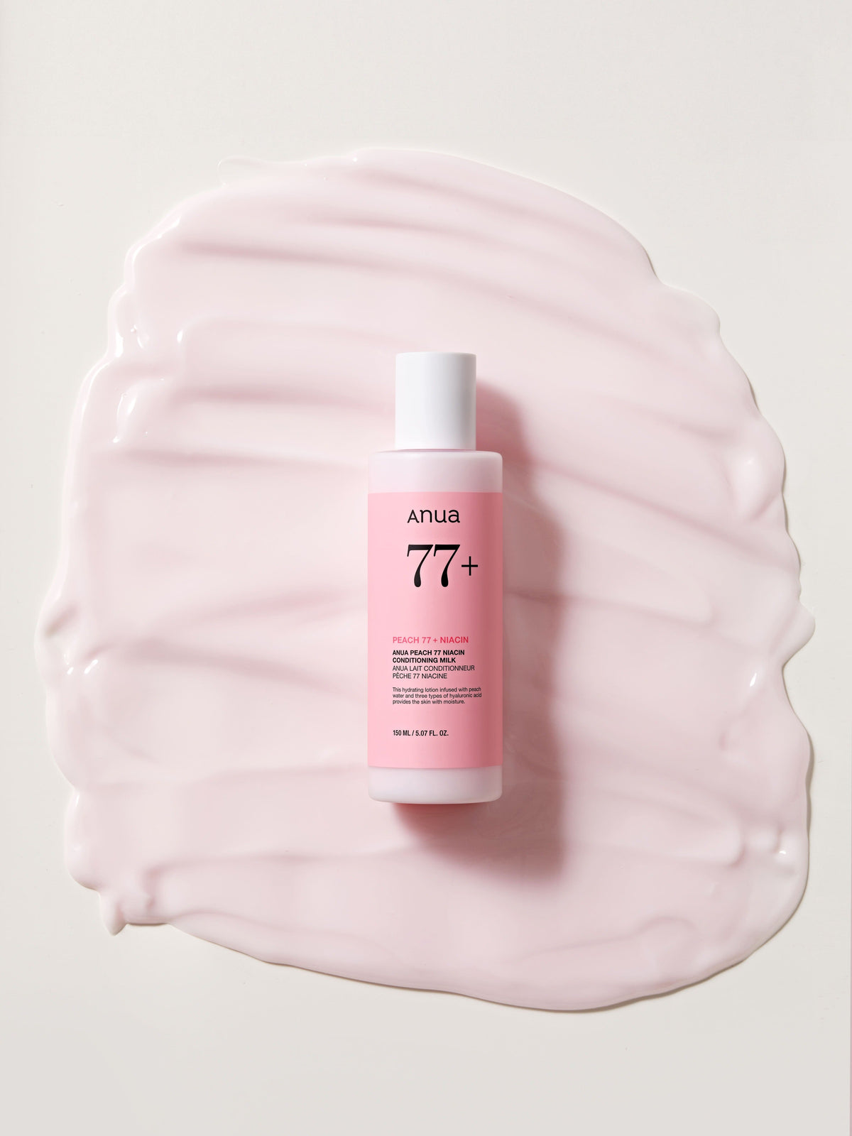 Flacon rose posé sur une large trace de lait hydratant