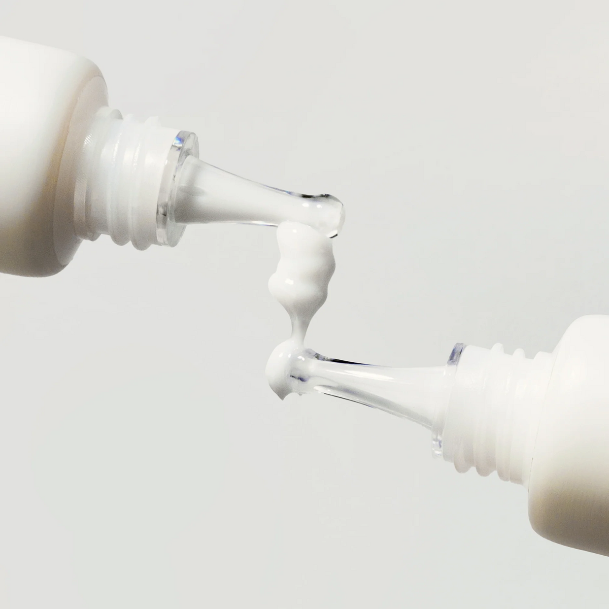 Gel-crème blanc entre les embouts de deux tubes