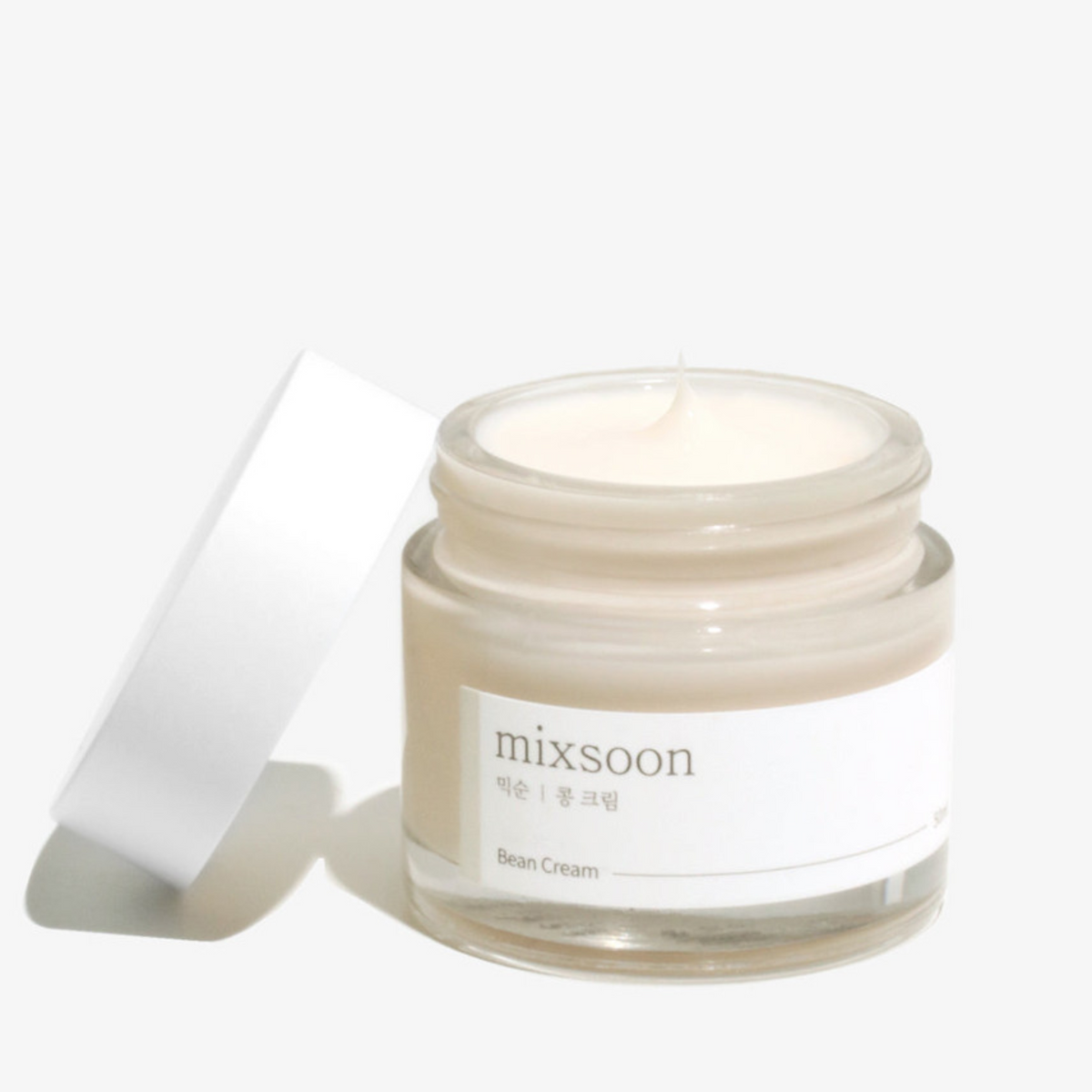 Pot ouvert de crème beige près de son couvercle blanc