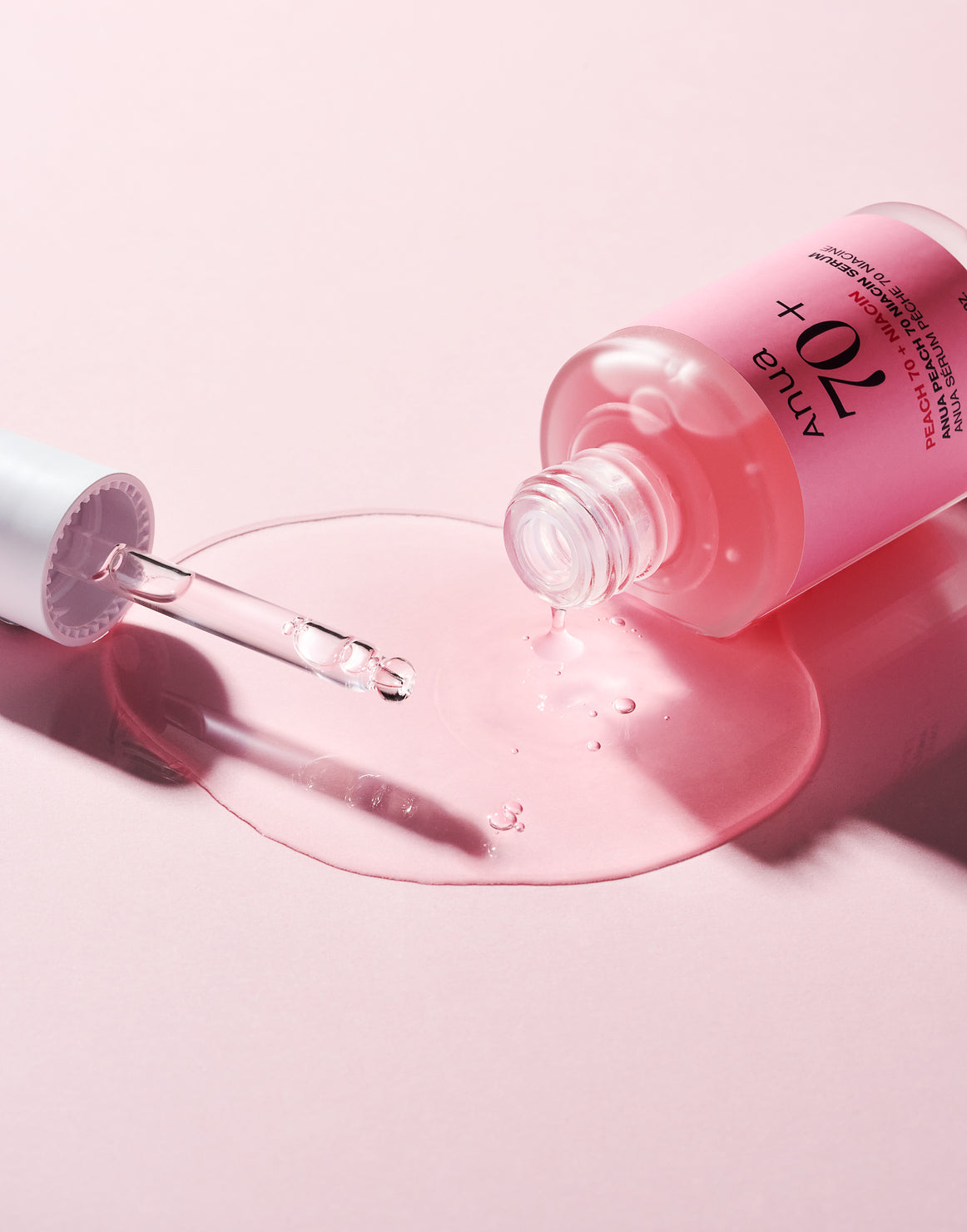 Sérum rose répandu près du flacon ouvert et de sa pipette