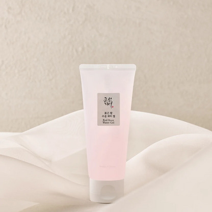Tube rose pâle de gel hydratant posé sur un tissu clair