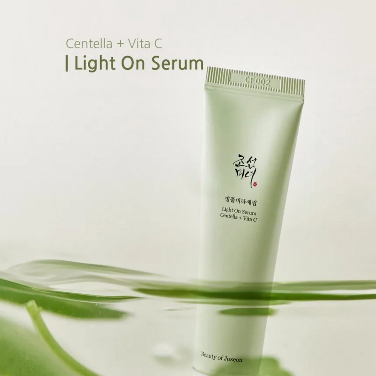 Tube vert de sérum près de feuilles, avec les mentions centella et vitamine C
