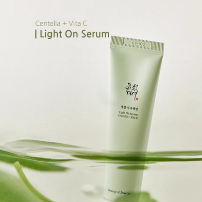 Tube vert de sérum près de feuilles, avec les mentions centella et vitamine C