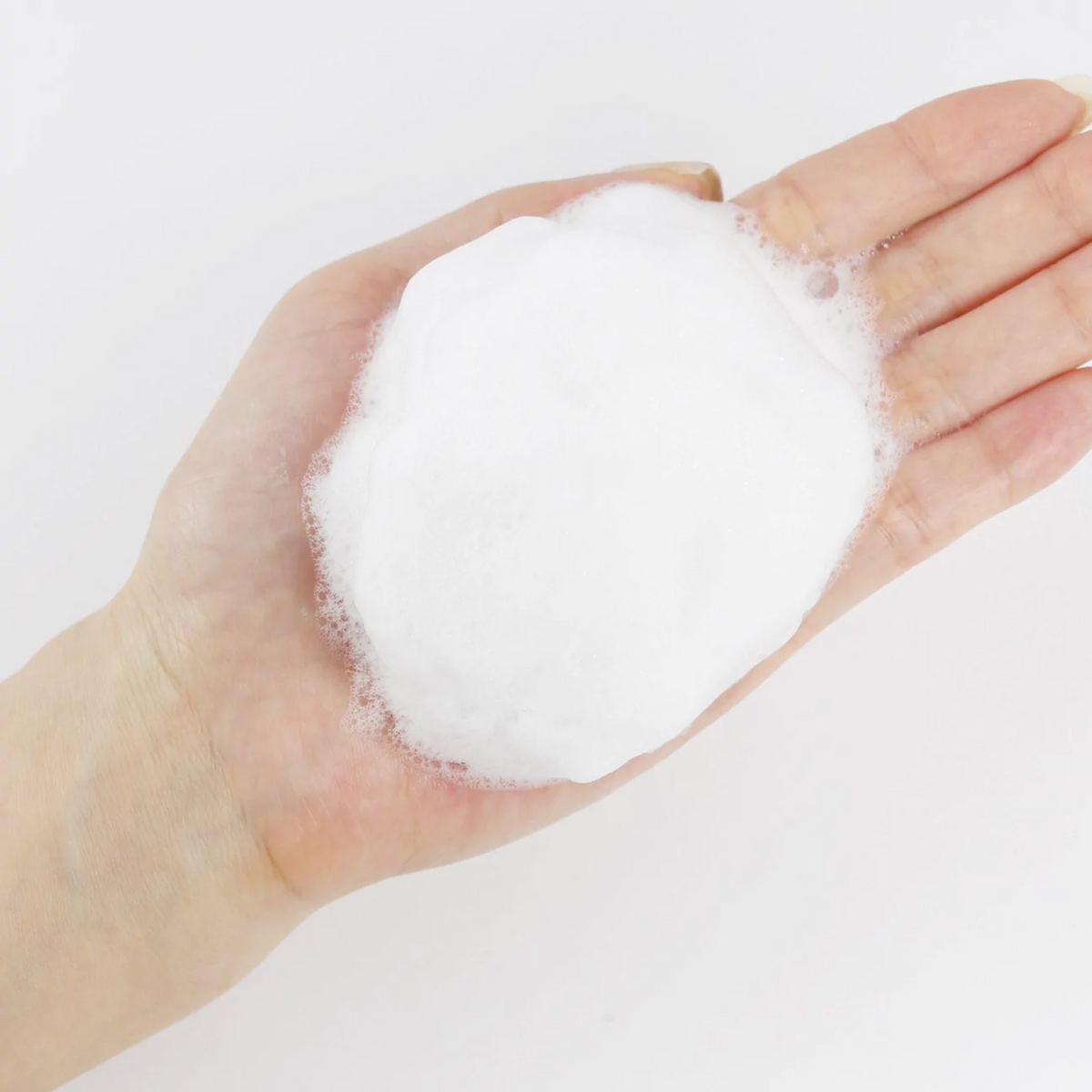 Boule de mousse blanche dans une paume ouverte