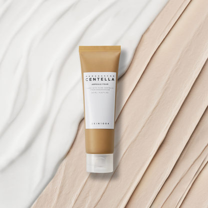 Tube doré de nettoyant sur des traces de crème blanche et beige
