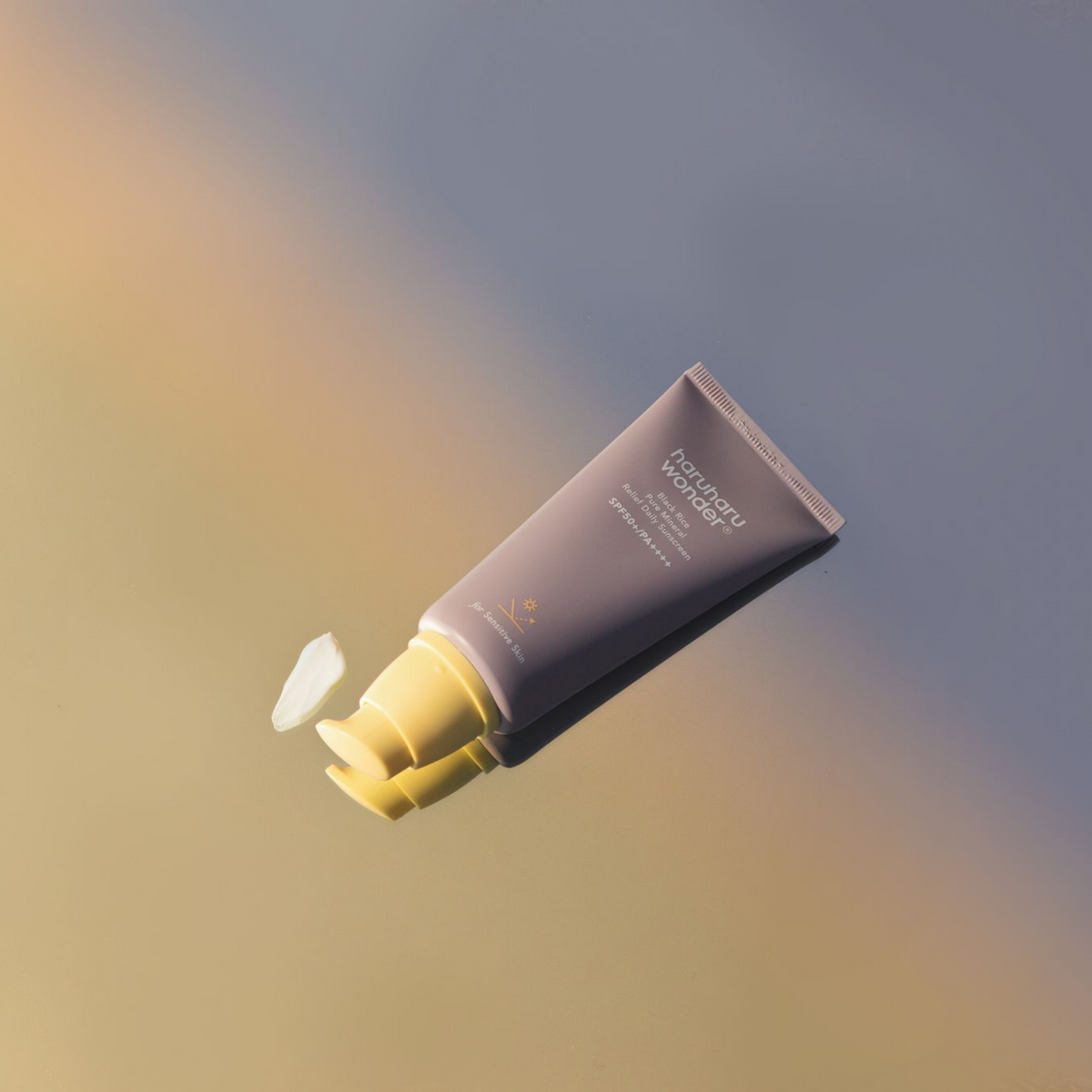 Tube mauve de solaire ouvert avec une touche de crème au bout de la pompe