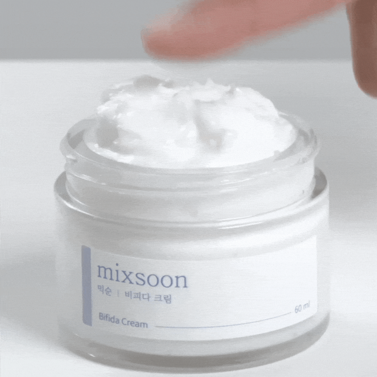 Doigt approché de la crème blanche dans le pot ouvert