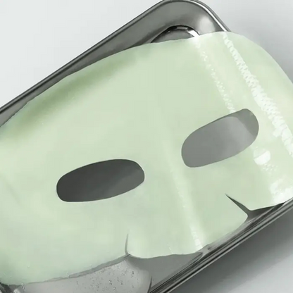 Masque hydrogel vert pâle déplié sur un plateau métallique