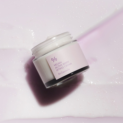 Pot de crème ouvert posé sur un tissu mauve