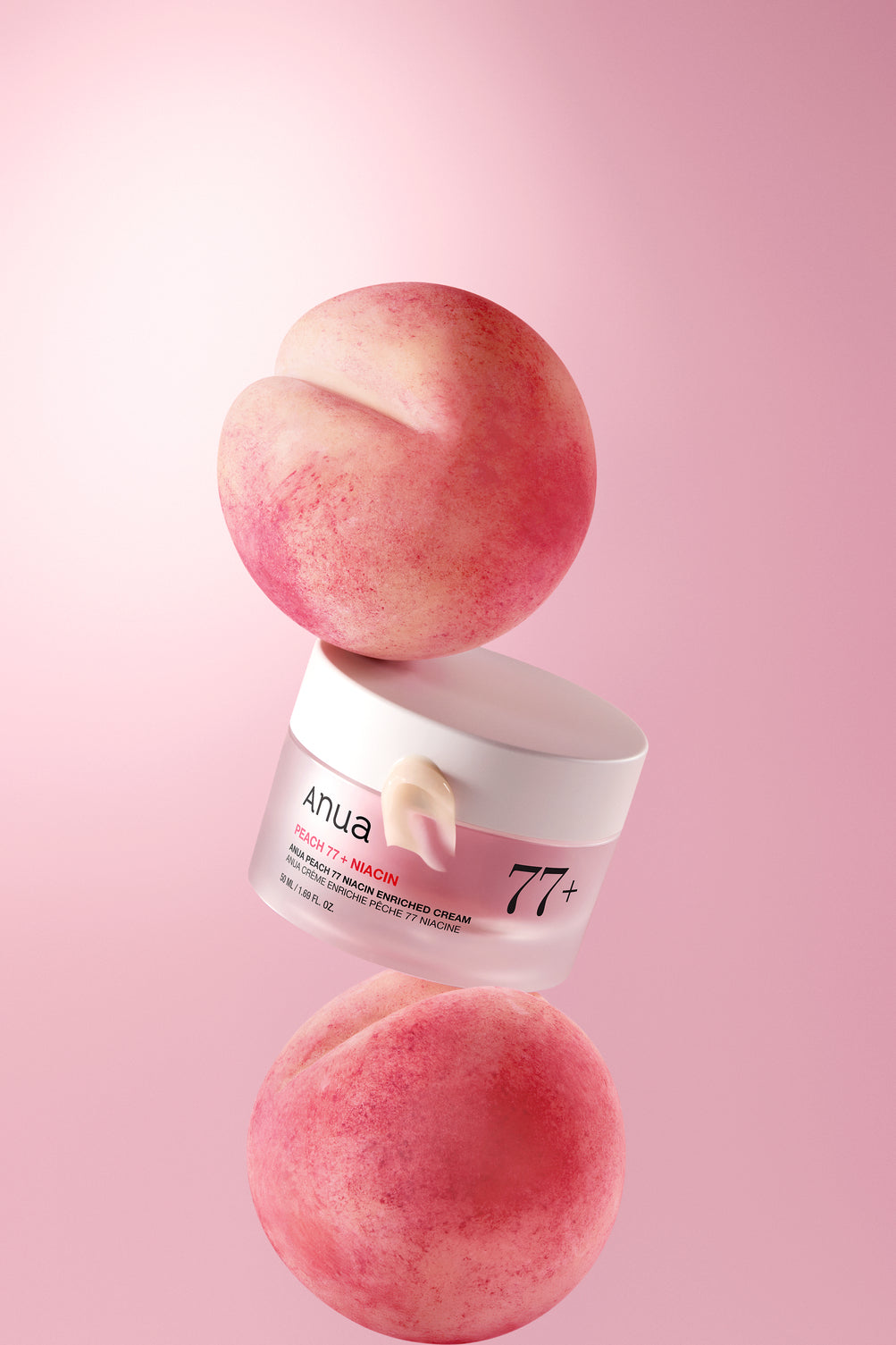 Pot de crème rose disposé entre deux pêches