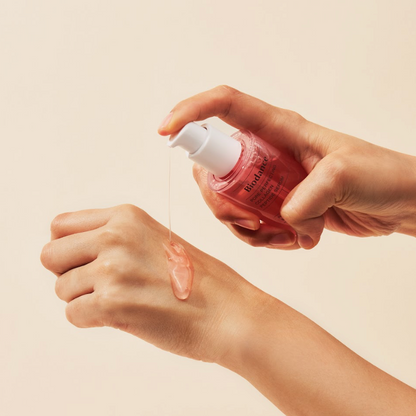 Sérum rose déposé sur le dos de la main avec la pompe