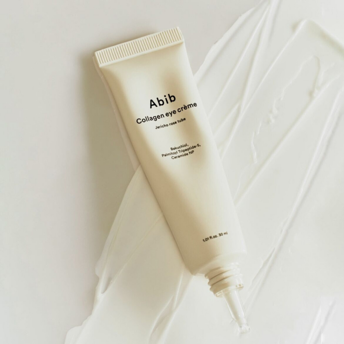 Tube de contour des yeux posé sur une trace de crème blanche
