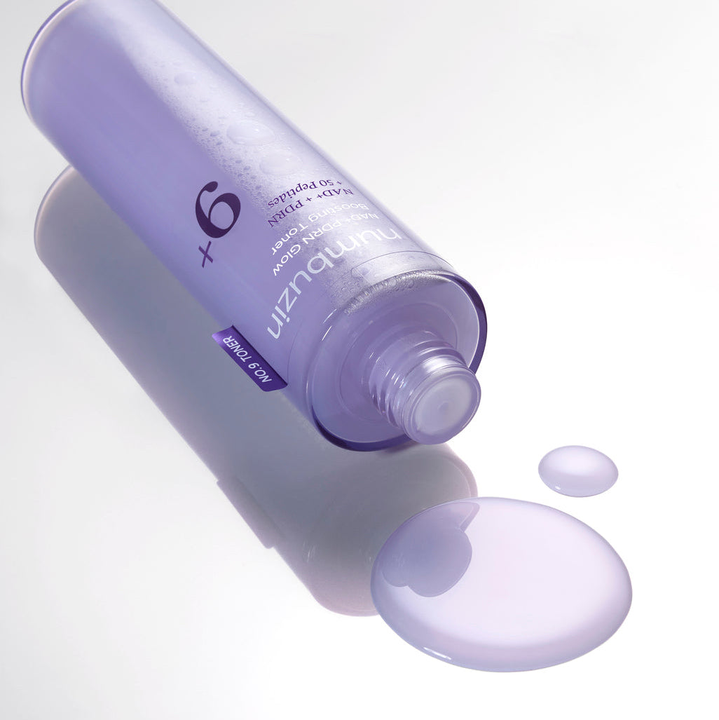 Flacon de lotion ouvert près de gouttes mauves