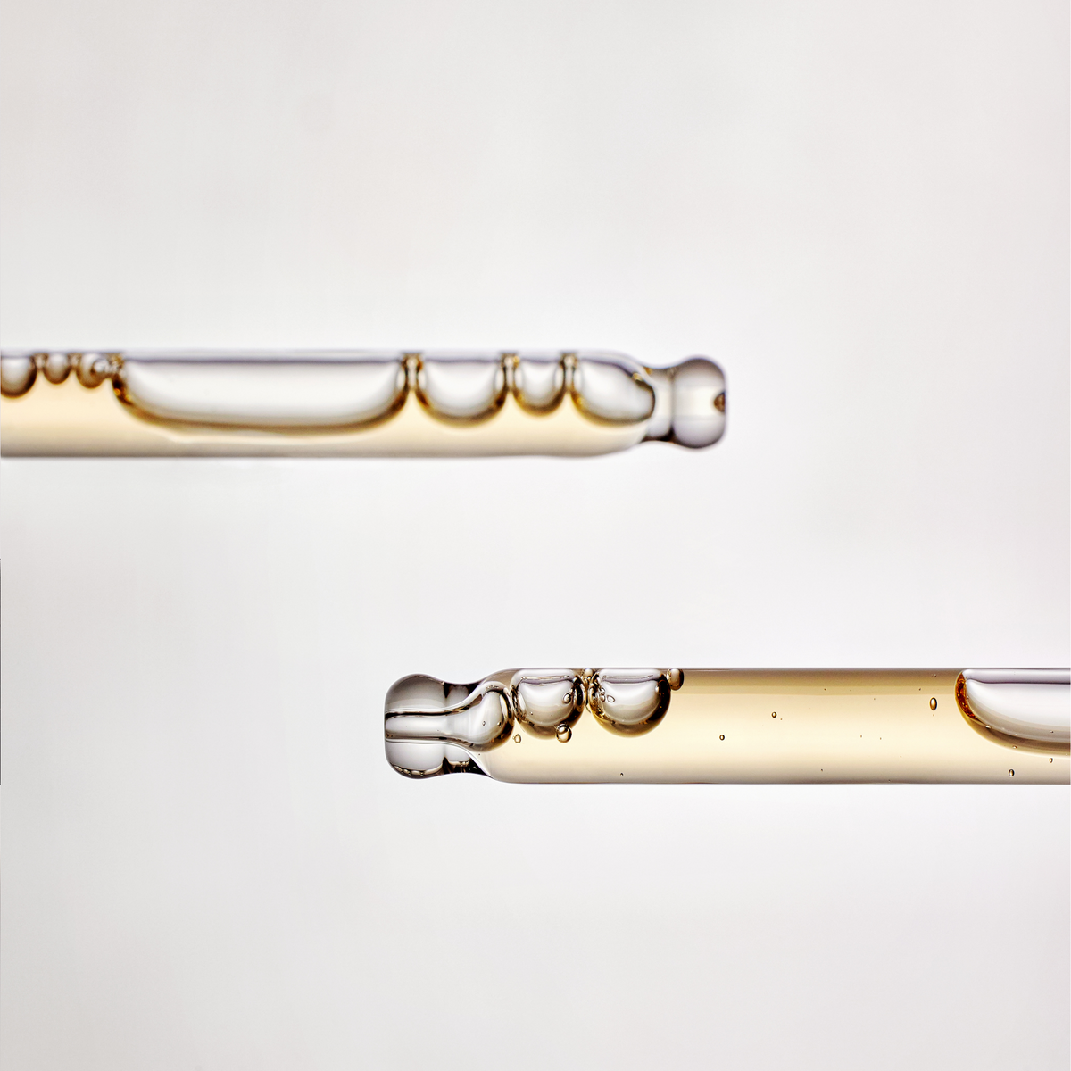 Gros plan du sérum doré à bulles dans deux pipettes