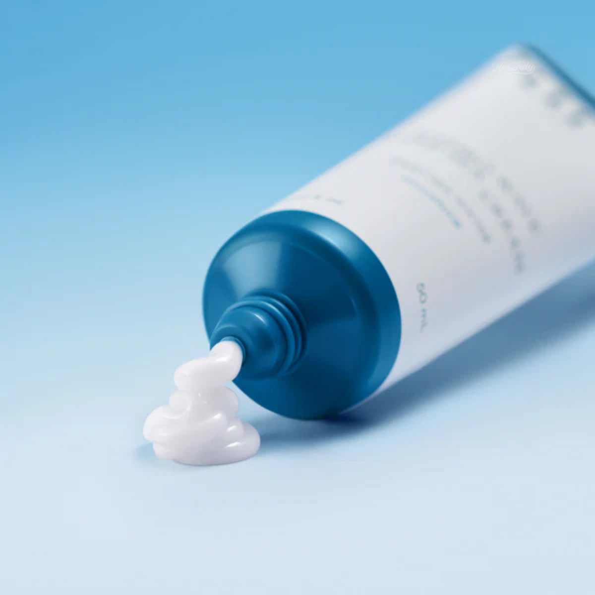 Crème blanche distribuée à la sortie du tube à embout bleu