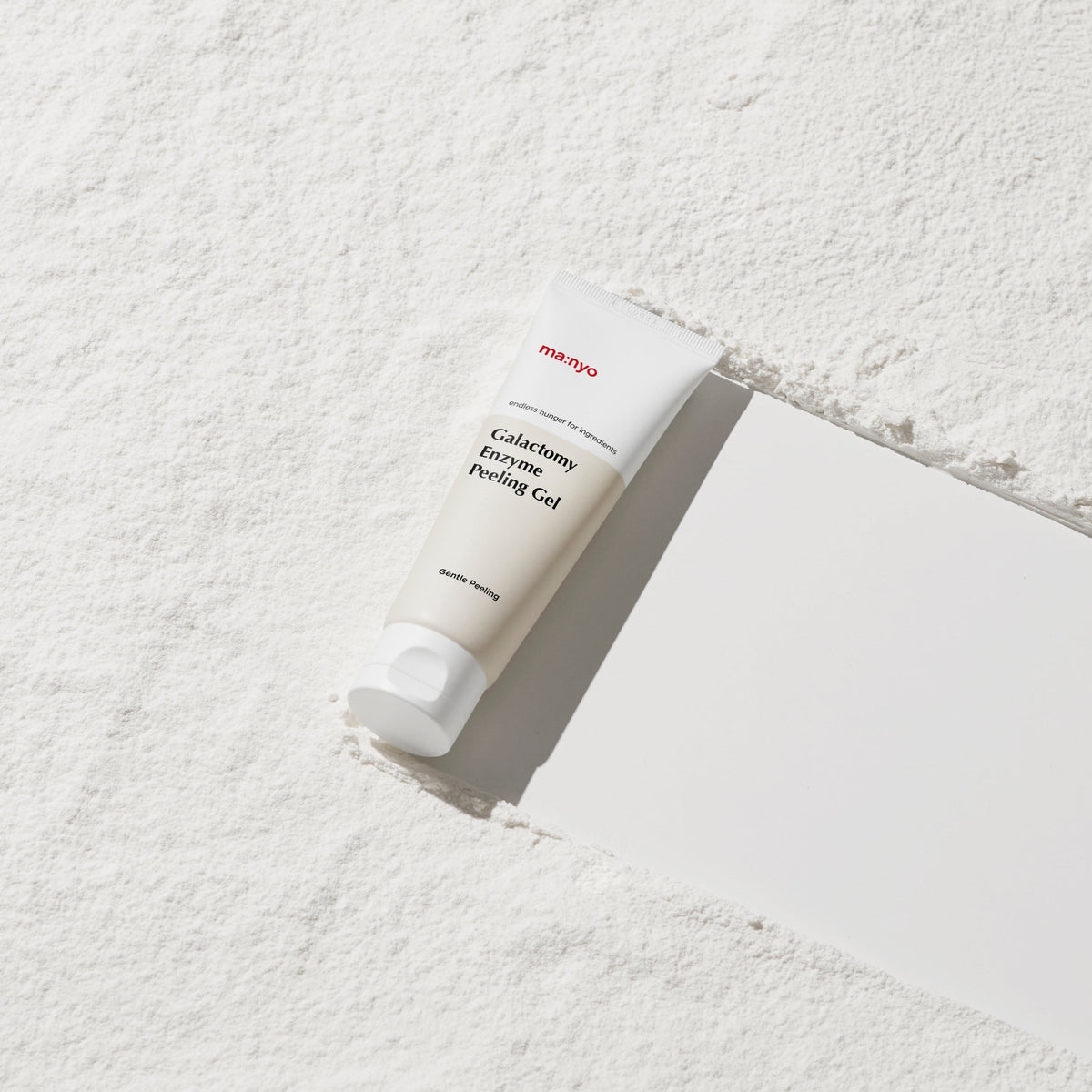 Tube blanc de gel exfoliant sur une surface poudrée