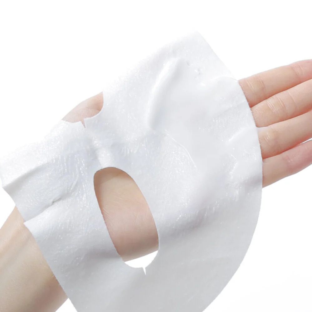 Tissu du masque blanc imbibé de crème déplié sur la main