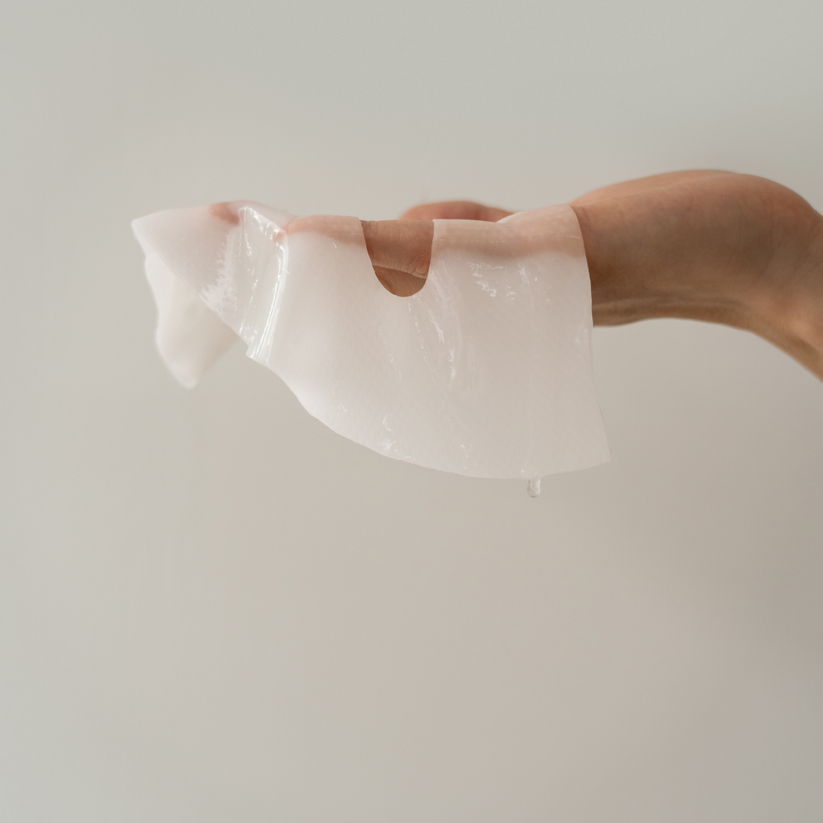 Masque en gel translucide déplié et tenu dans la main