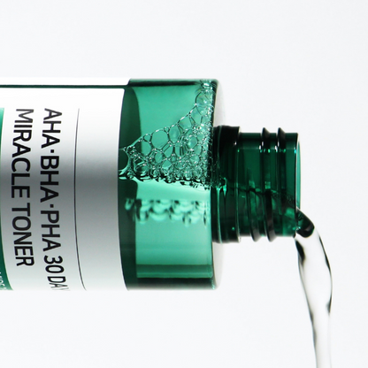 Lotion transparente versée depuis le flacon vert ouvert