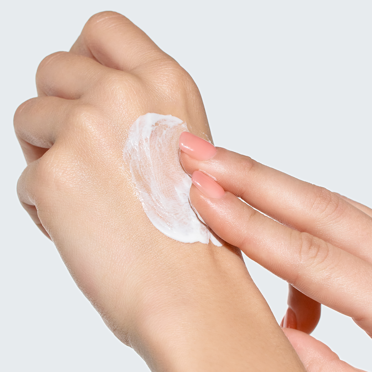 Crème solaire blanche étalée avec les doigts sur le dos de la main