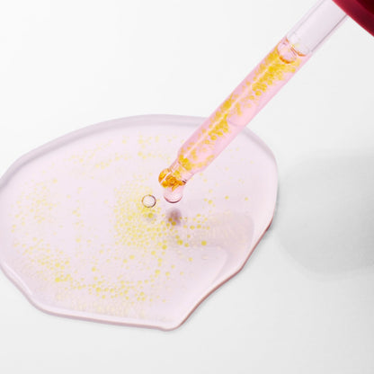 Pipette de sérum rose à particules jaunes au-dessus d&