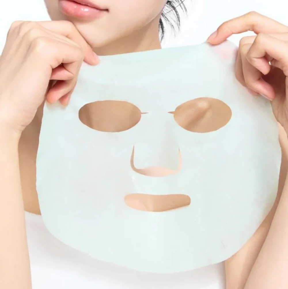 Masque fin vert pâle déplié et tenu entre les mains